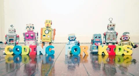 The words CODING FOR KIDS  with rtro robot toys on a wooden floor Stock Photos