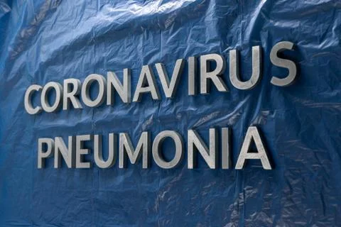 The words coronavirus pneumonia laid with silver letters on crumpled blue pla Stock Photos
