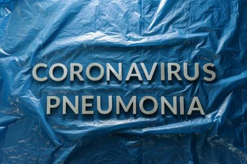 The words coronavirus pneumonia laid with silver letters on crumpled blue pla Stock Photos