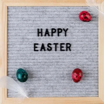 The words Happy Easter on grey felt letter board decorated with quail eggs an Stock Photos