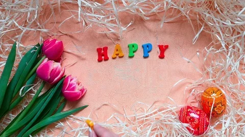 Words "Happy Easter", pink tulips, easter eggs among straw Stock Footage 104084864