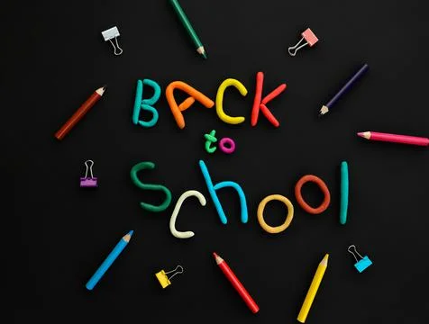 Words of multi-colored plasticine back to school and pens, paper clips, on black Stock Photos