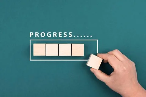 The words progress is standing over the loading bar, hand puts last cube t... Stock Photos
