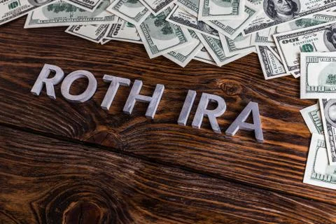 Words ROTH IRA laid on wooden surface with metal letters and us dollar banknotes Stock Photos