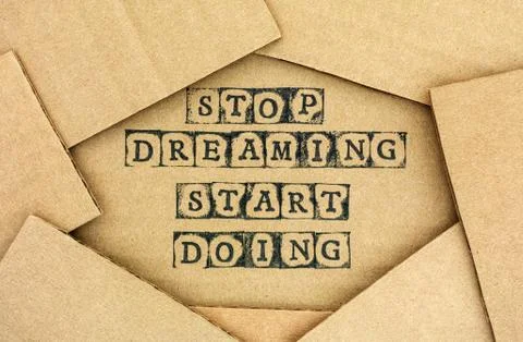 Words Stop Dreaming Start Doing make by black alphabet stamps on cardboard Stock Photos