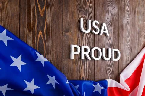 Words USA proud laid with silver metal letters on brown wooden surface with flag Stock Photos