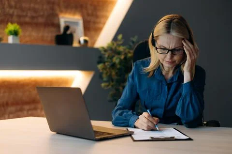 Work after the end of the working day. Responsible tired adult caucasian female Stock Photos