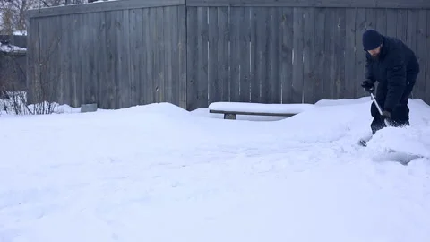 Work after snowy night. Man with a shovel removing the snow from his yard on a Stock Footage 87642185