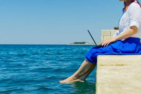 Work from anywhere. Side view of young woman, female freelancer in straw hat Stock Photos