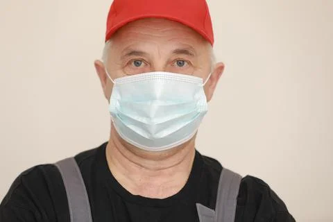 Work are done. Portrait of worker man with medical mask in red overall, black t Stock Photos