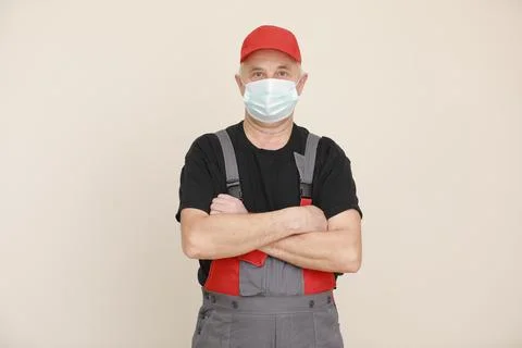 Work are done. Portrait of worker man with medical mask in red overall, black t Stock Photos