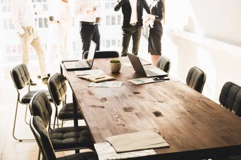Work area on the table in the foreground. A team of young businessmen working Stock Photos