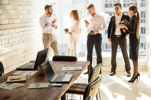 Work area on the table in the foreground. A team of young businessmen working Stock Photos