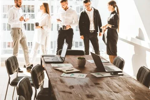 Work area on the table in the foreground. A team of young businessmen working Stock Photos