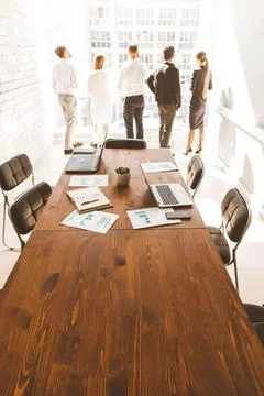 Work area on the table in the foreground. A team of young businessmen working Stock Photos