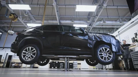 The work of an automatic lift in a car workshop. Modern car service with Stock Footage 195738756