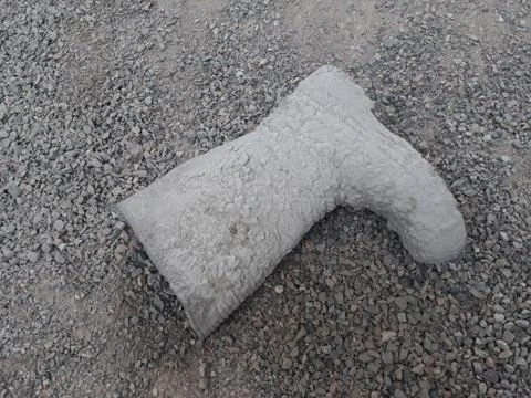Work boots covered with cement lying on the gravel Stock Photos