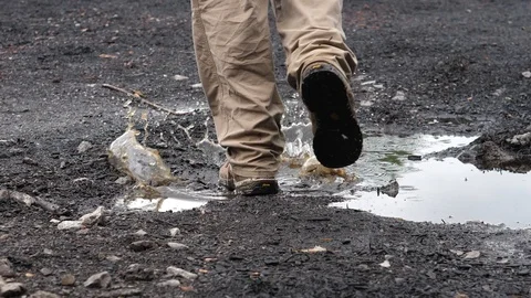 Work boots walking through puddle Stock Footage