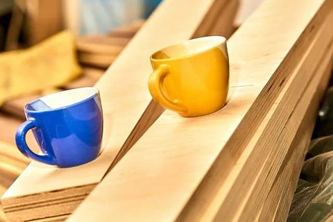 Work break, tea coffee time. Blue and yellow cups in carpentry on wooden planks Stock Photos