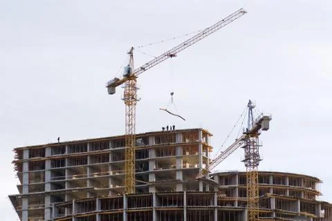 Work of builders and crane in the construction of a multi-storey building. Stock Photos