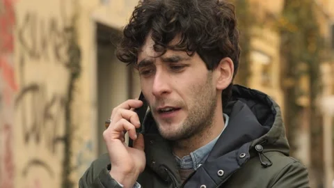 Work call - young man on the street tals on phone with his boss Video stock 240339113