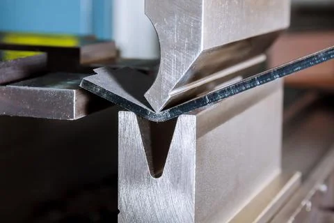 Work on a CNC bending machine in a factory. Sheet metal bending on a high-pre Stock Photos