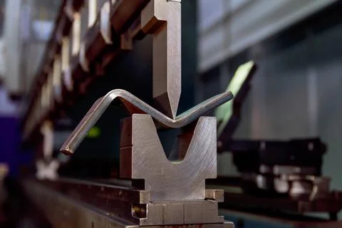 Work on a CNC bending machine in a factory. Sheet metal bending on a high-pre Stock Photos
