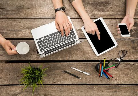 Work collaboration at a rustic table with laptop, tablet, and smartphone during Stock Photos
