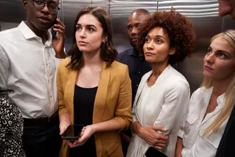 Work colleagues standing in an elevator at their office, close up Stock Photos