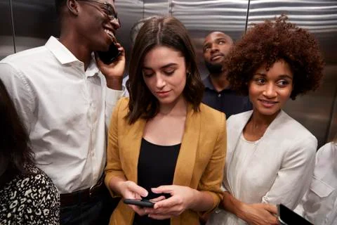Work colleagues standing in an elevator at their office, close up Stock Photos