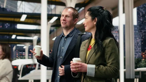 Work colleagues talking and walking inside modern bus terminal, enjoying coffee Stock Footage 340203393