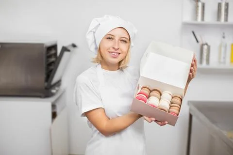 Work in confectionery workshop. Handmade macarons. Smiling pretty young woman Foto stock