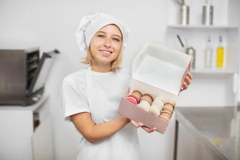 Work in confectionery workshop. Handmade macarons. Smiling pretty young woman 스톡 사진