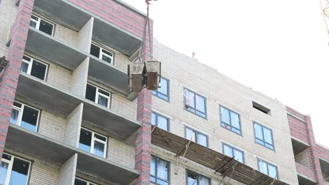 The work of a construction tower crane on a new building lifting baths Stock Footage 161185363