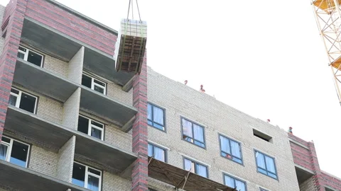 The work of a construction tower crane on a new building lifting materials Stock Footage 161185419