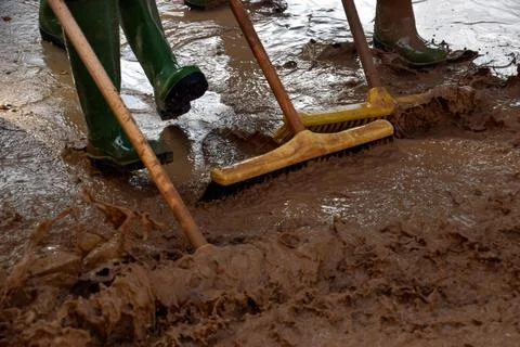 Work crews remove scum and mud from an area affected by flooding. Stock Photos