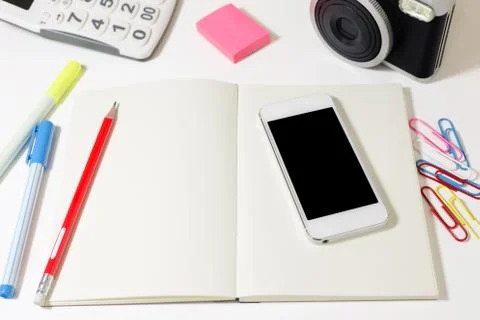 Work desk with blank notebook, phone, camera, calculator and pencil Stock Photos