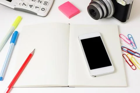 Work desk with blank notebook, smart phone, camera, calculator and pencil Фото