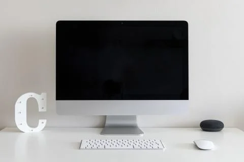 Work desk with a computer and the letter C against a white wall 스톡 사진