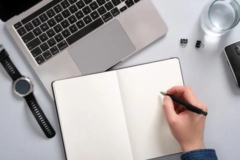 Work desk with computer, notepad, writing supplies. A man's hand writing in a Stock Photos