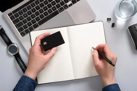 Work desk with computer, notepad, writing supplies. In one hand a man holds a Foto stock