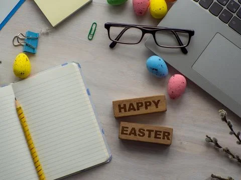 Work desk with devices and easter holiday multicolored eggs on wood background Stock-Fotos