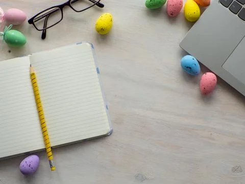 Work desk with devices and easter holiday multicolored eggs on wood background Stock Photos