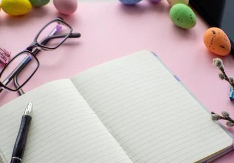Work desk with devices and easter holiday multicolored eggs on pink background Stock-Fotos