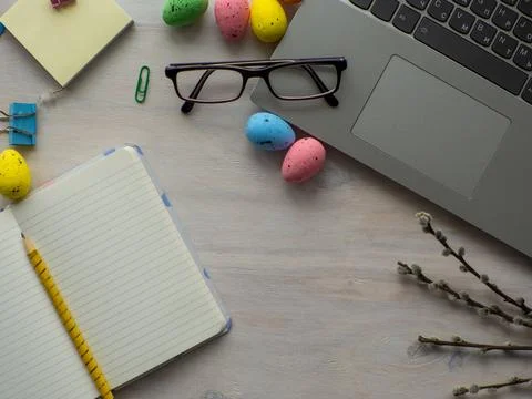 Work desk with devices and easter holiday multicolored eggs on wood background Stock Fotos