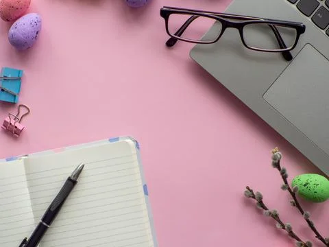 Work desk with devices and easter holiday multicolored eggs on pink backgroun Stock-Fotos