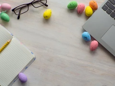 Work desk with devices and easter holiday multicolored eggs on wood background Stock-Fotos