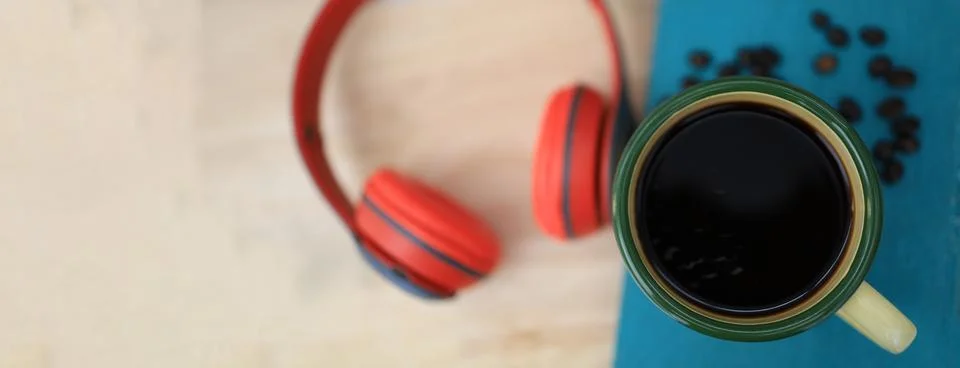 The work desk has a coffee cup and red headphones and office supplies. Stock Photos