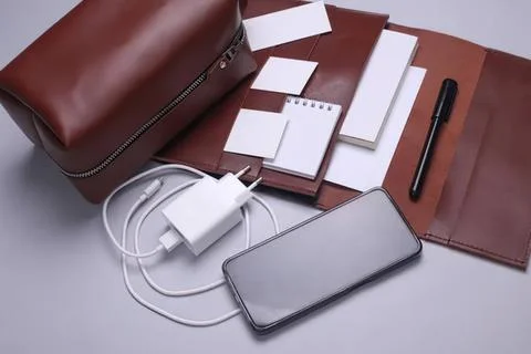 Work desk with phone notepad pen charger and bag Stock Photos
