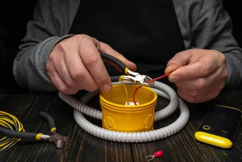 Work on electrical wires using tools and connectors in a dark workspace dur.. Stock Photos